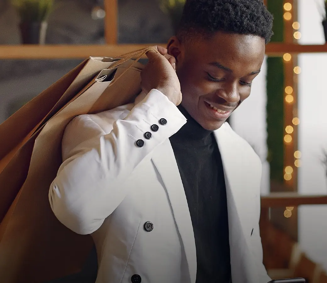 A man in a white blazer carrying shopping bags on his shoulder